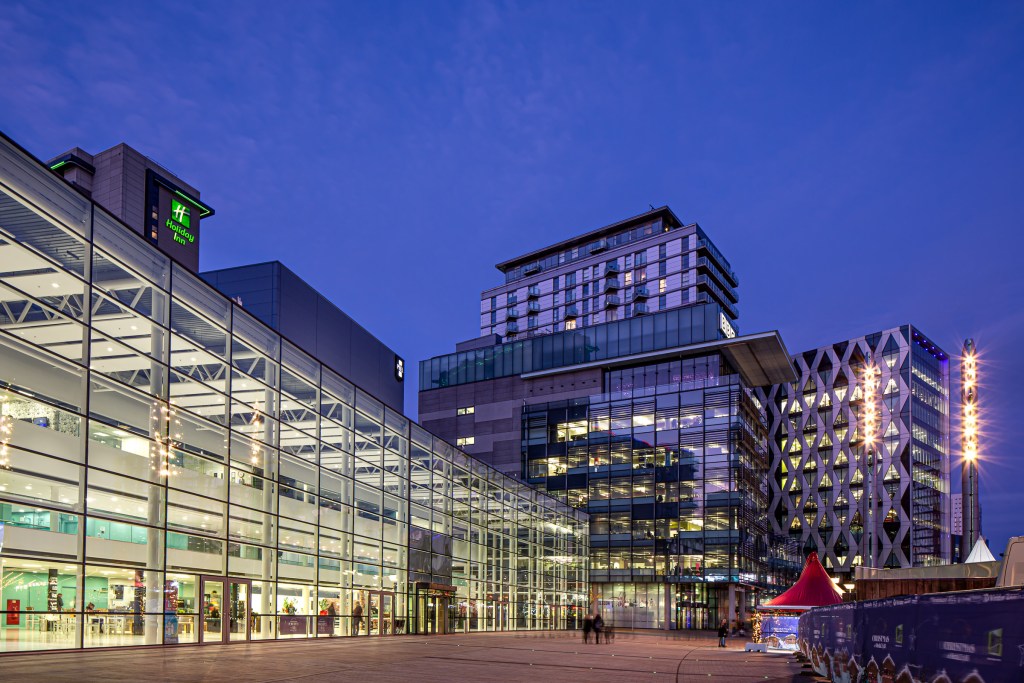 Modern glass-fronted city buildings at dusk, with visible internal lighting and geometric design, symbolising digital structure and AI-era visibility. Photograph by Diane Heart (Di Jones Photography).